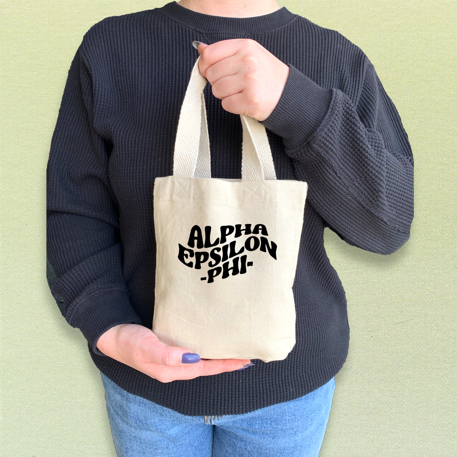Alpha Epsilon Phi tote bag held by a sorority woman, featuring the AEPhi letters in a vibrant design.
