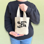 Alpha Xi Delta mini sorority tote held by a sister, featuring bold and clean Greek letters.