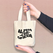 Alpha Chi Omega woman holding a stylish mini tote bag with bold Greek letters printed on the front.