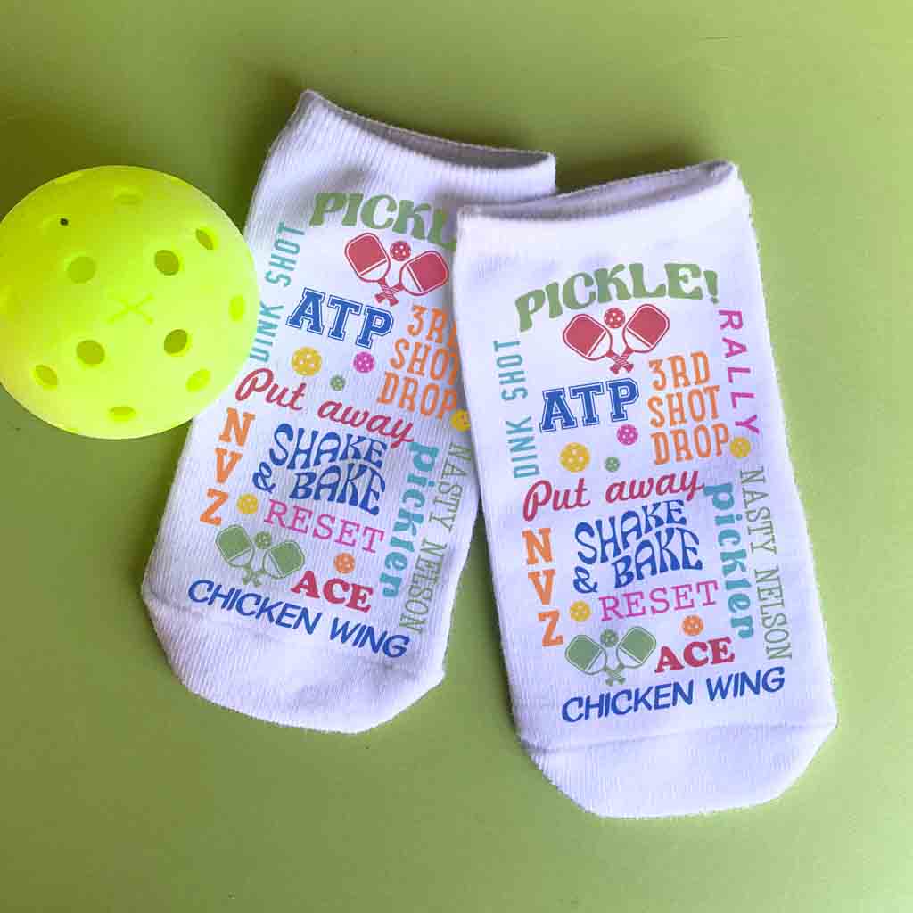 A full print pattern with different funny pickleball sayings printed on white no show footie socks for men and women.