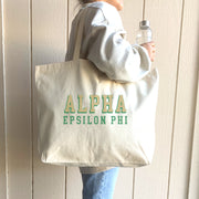 Alpha Epsilon Phi tote bag with dimensional text, shown on the shoulder of a fashionable sorority member.
