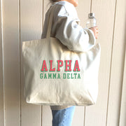 Alpha Gamma Delta member carrying a stylish tote with raised 3D Alpha Gamma Delta name design over one shoulder.