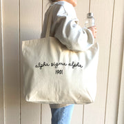 Alpha Sigma Alpha – A student models an Alpha Sigma Alpha sorority tote bag, casually slung over her shoulder as she walks through campus.
