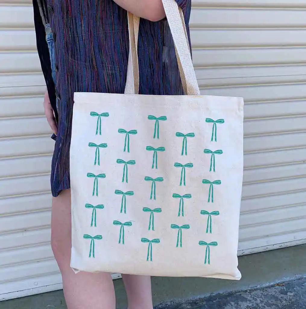 This stylish shoulder tote features a step and repeat pattern of a coquette bow, available in 6 fun fashion colors.