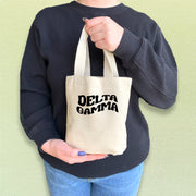 Delta Gamma woman carrying a DG mini tote with printed Greek letters in a sleek font.