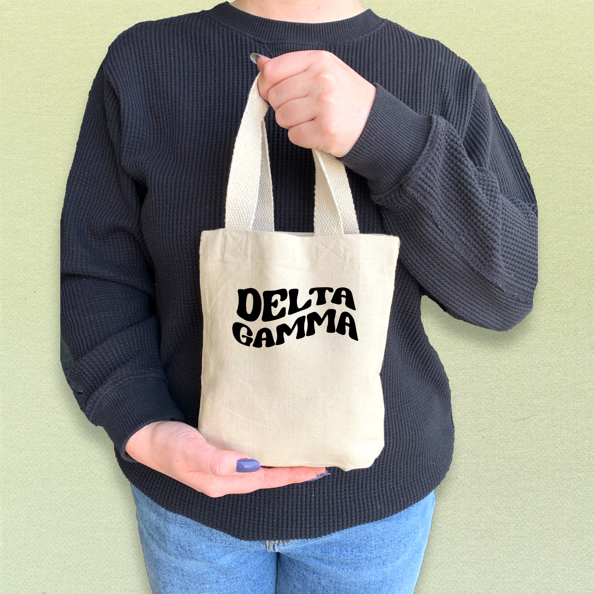 Delta Gamma woman carrying a DG mini tote with printed Greek letters in a sleek font.