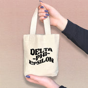 Delta Phi Epsilon sorority woman holding a mini tote bag with Delta Phi Epsilon’s classic letters.