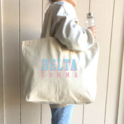 Delta Gamma tote bag with raised-style Greek letters, slung over the shoulder of a DG member in denim.