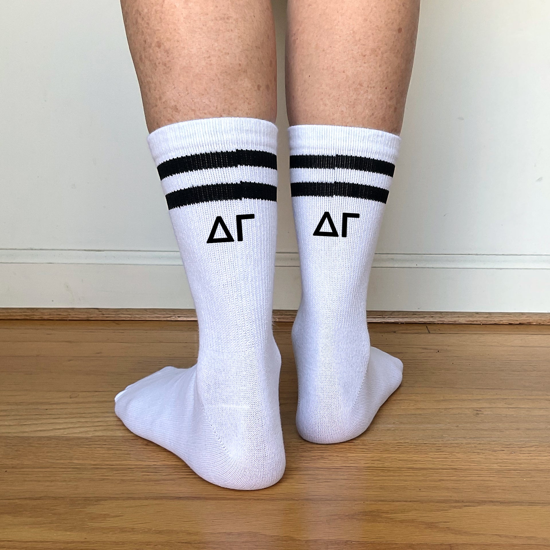 White crew socks with black stripes and "??" Greek letters printed on the back of each leg.