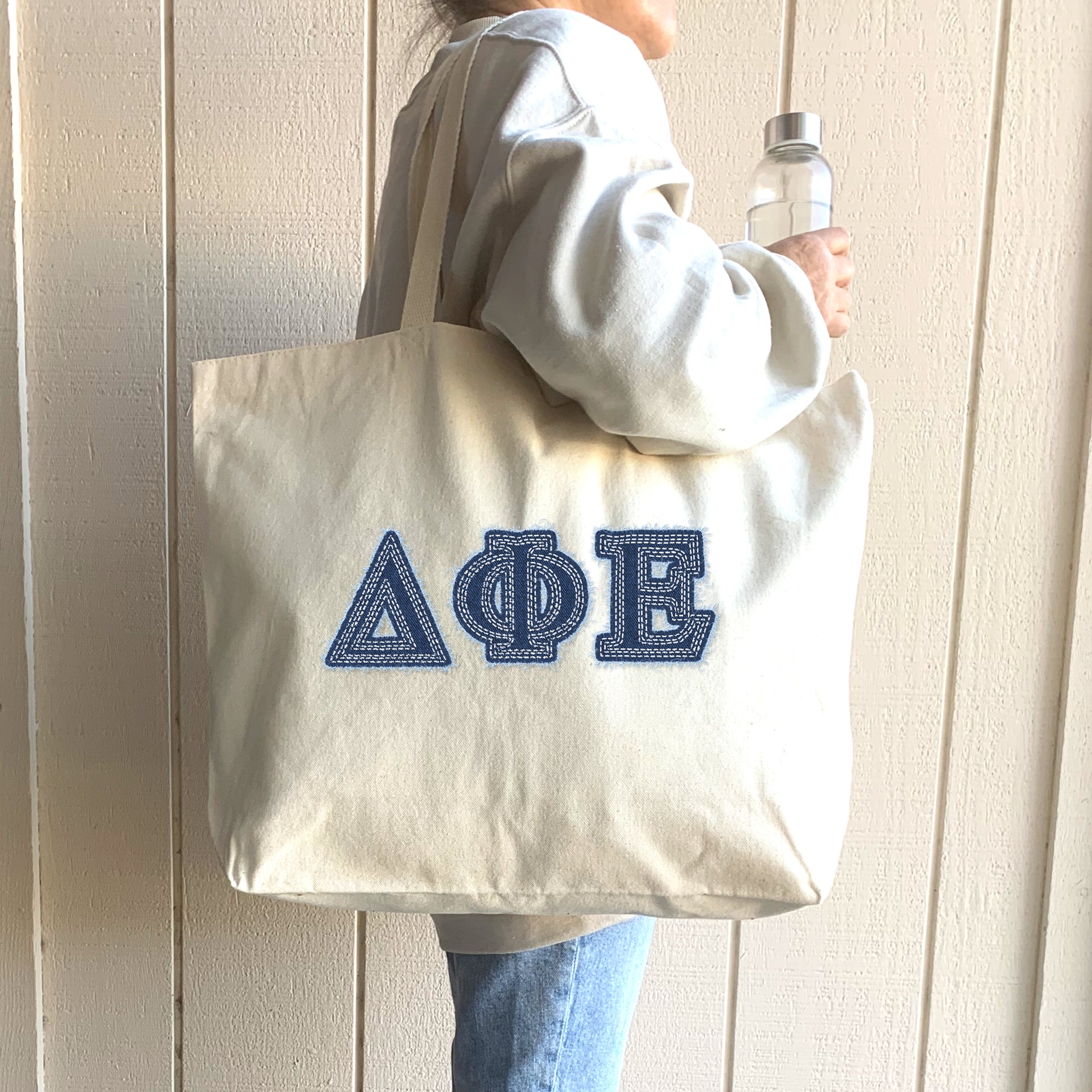 A stylish student carries her denim Delta Phi Epsilon tote at a sorority retreat.