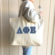 Woman carries her Delta Phi Epsilon tote to a study session on campus.