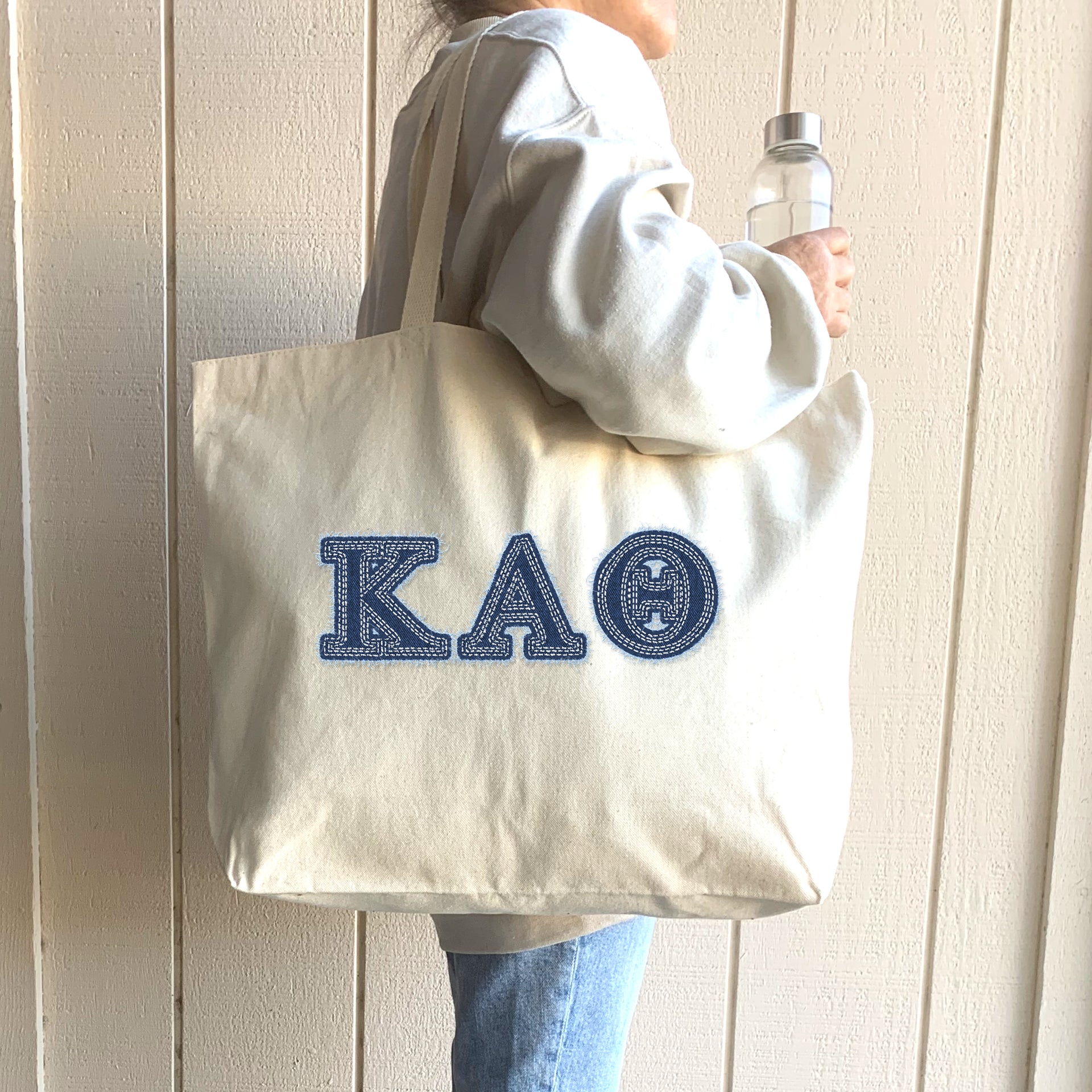 A student dressed in black and gold carries her denim Kappa Alpha Theta tote to a leadership workshop.