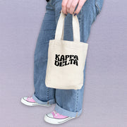 Kappa Delta woman holding her KD mini tote bag, customized with bright sorority letters.