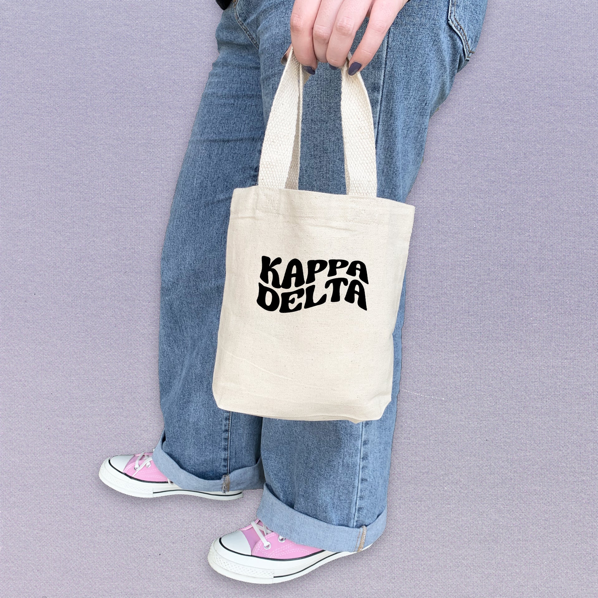 Kappa Delta woman holding her KD mini tote bag, customized with bright sorority letters.