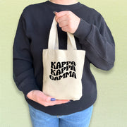 Kappa Kappa Gamma member showing off a mini tote bag printed with bold KKG letters.