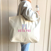 Pi Beta Phi sorority tote with raised name design, carried on the shoulder of a Pi Phi student walking to class.