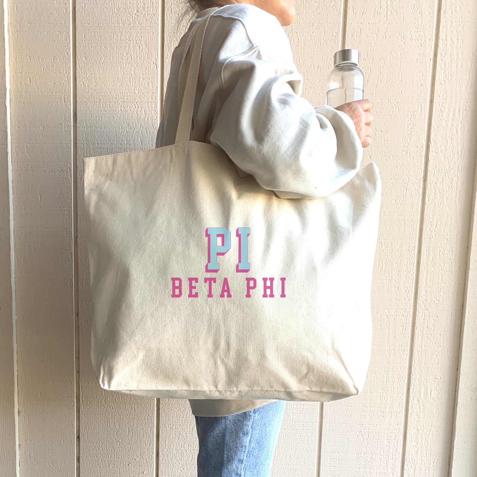 Pi Beta Phi sorority tote with raised name design, carried on the shoulder of a Pi Phi student walking to class.