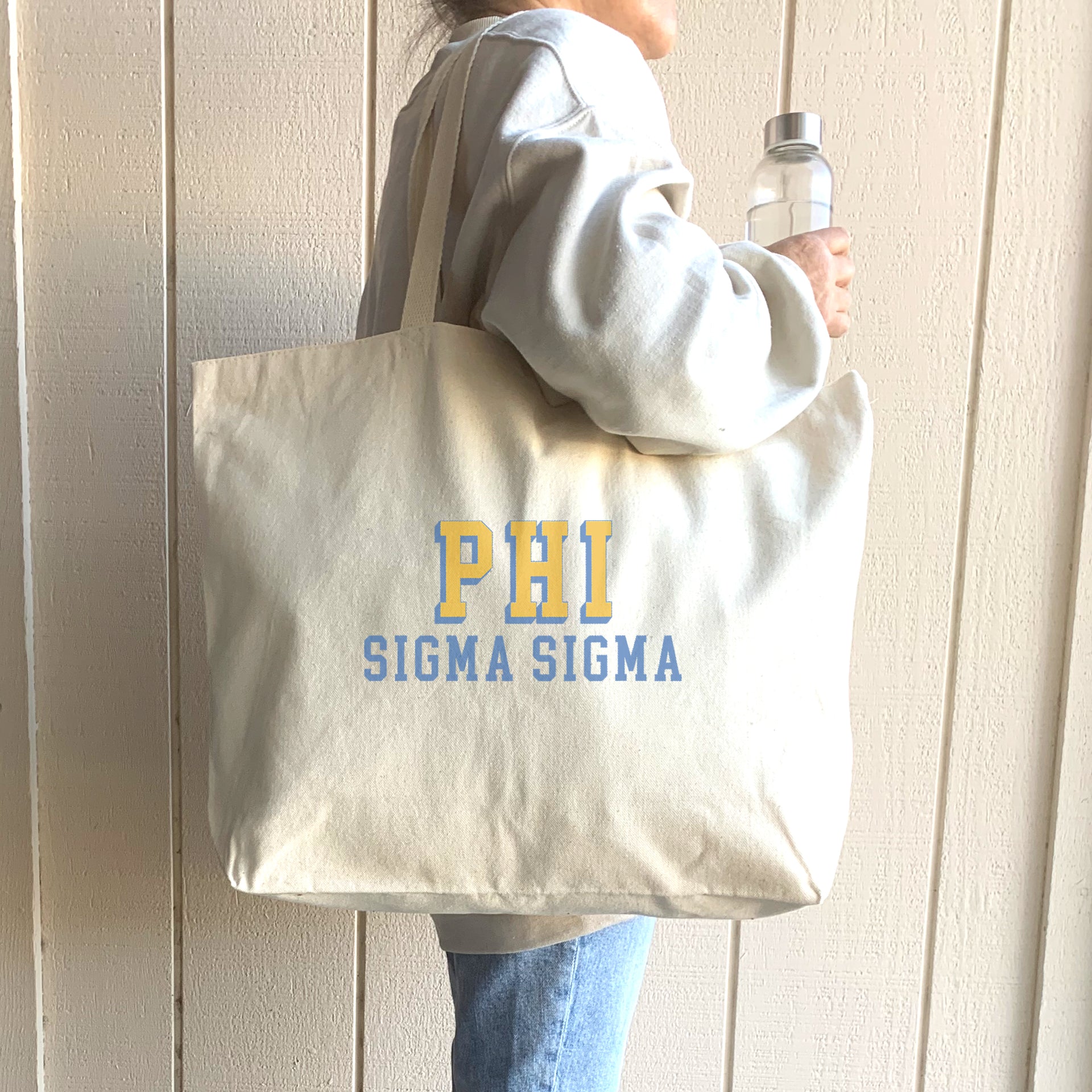 Phi Sigma Sigma tote bag featuring bold 3D sorority letters, slung over the shoulder of a member in casual wear.
