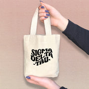 Sigma Delta Tau member holding a mini SDT tote bag, perfect for Greek events and daily use.