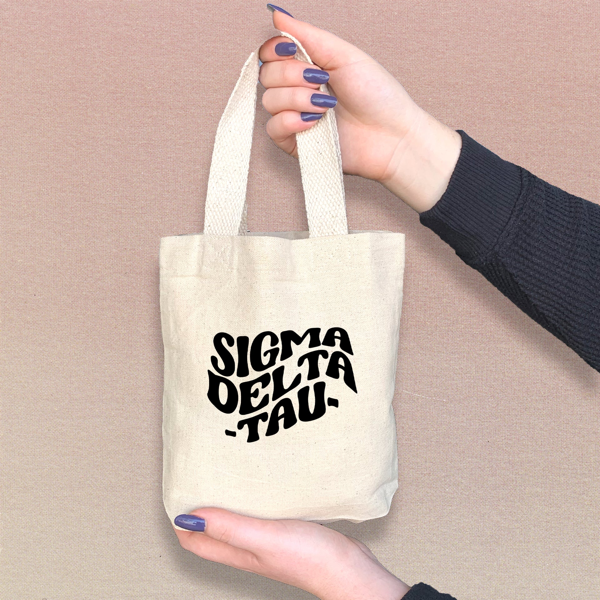 Sigma Delta Tau member holding a mini SDT tote bag, perfect for Greek events and daily use.