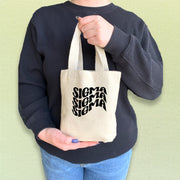 Sigma Sigma Sigma sister carrying a mini Tri Sigma tote bag in casual campus style.