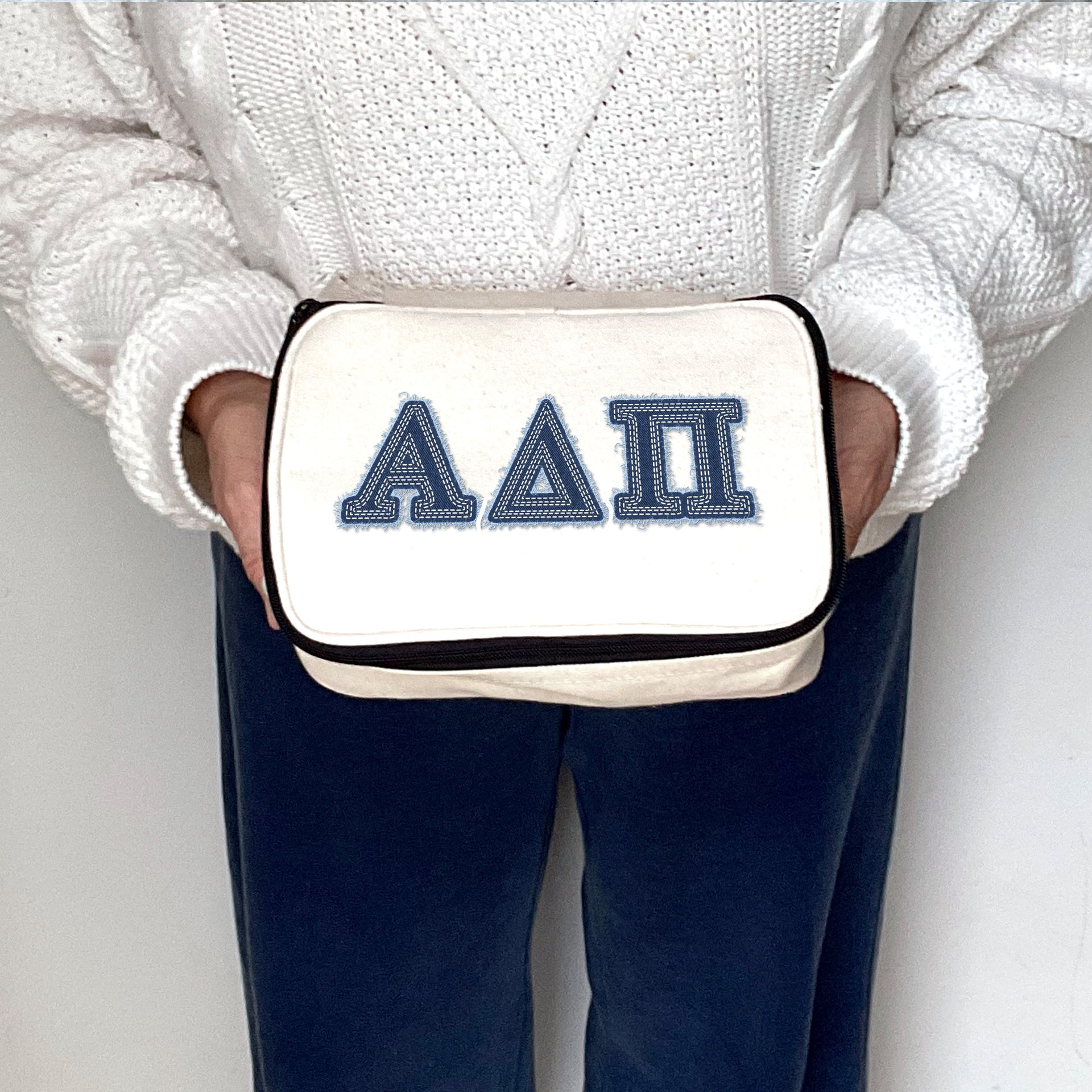 Alpha Delta Pi cosmetic bag with denim-style ADPi Greek letters, held by a sorority member