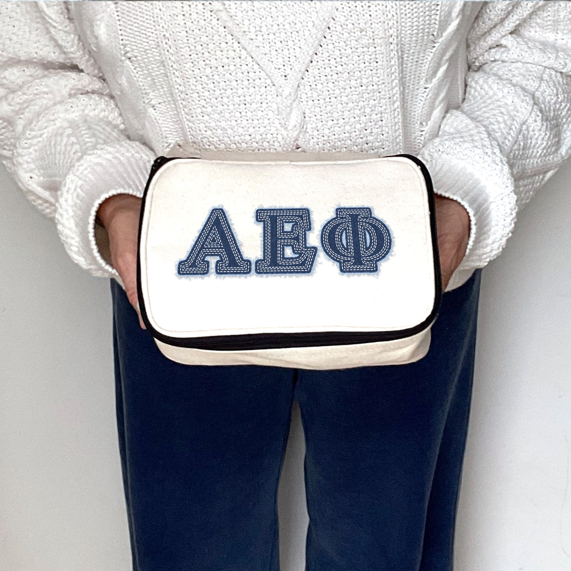 Alpha Epsilon Phi sorority member holding a canvas cosmetic bag with denim-style AEPhi letters.