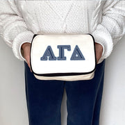 Alpha Gamma Delta canvas pouch featuring denim-style Greek letters, held by a sorority member.