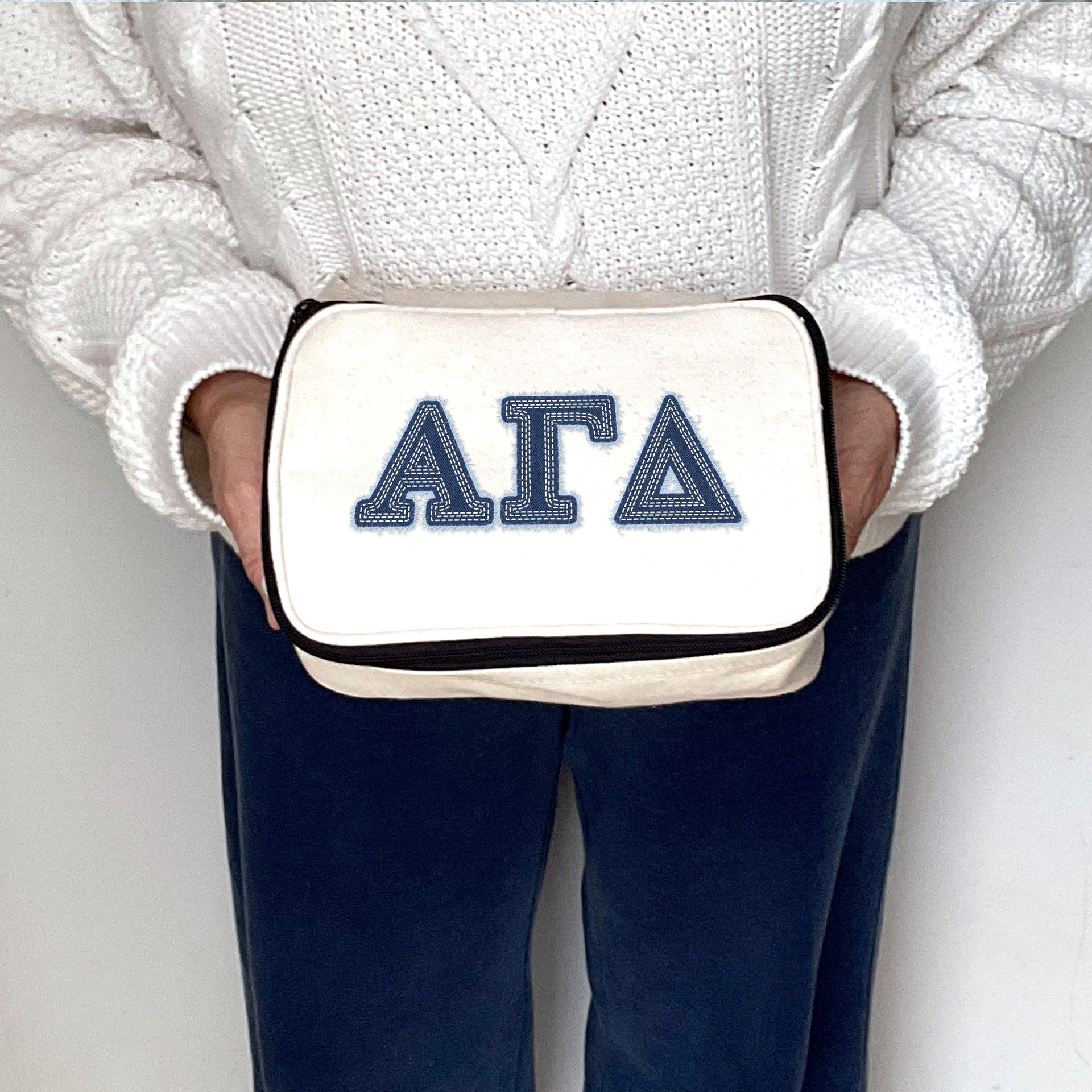 Alpha Gamma Delta denim-style Alpha Gamma Delta cosmetic bag held for display by a sorority sister.