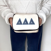 Delta Delta Delta makeup bag featuring Theta denim Greek letters, held for product styling.