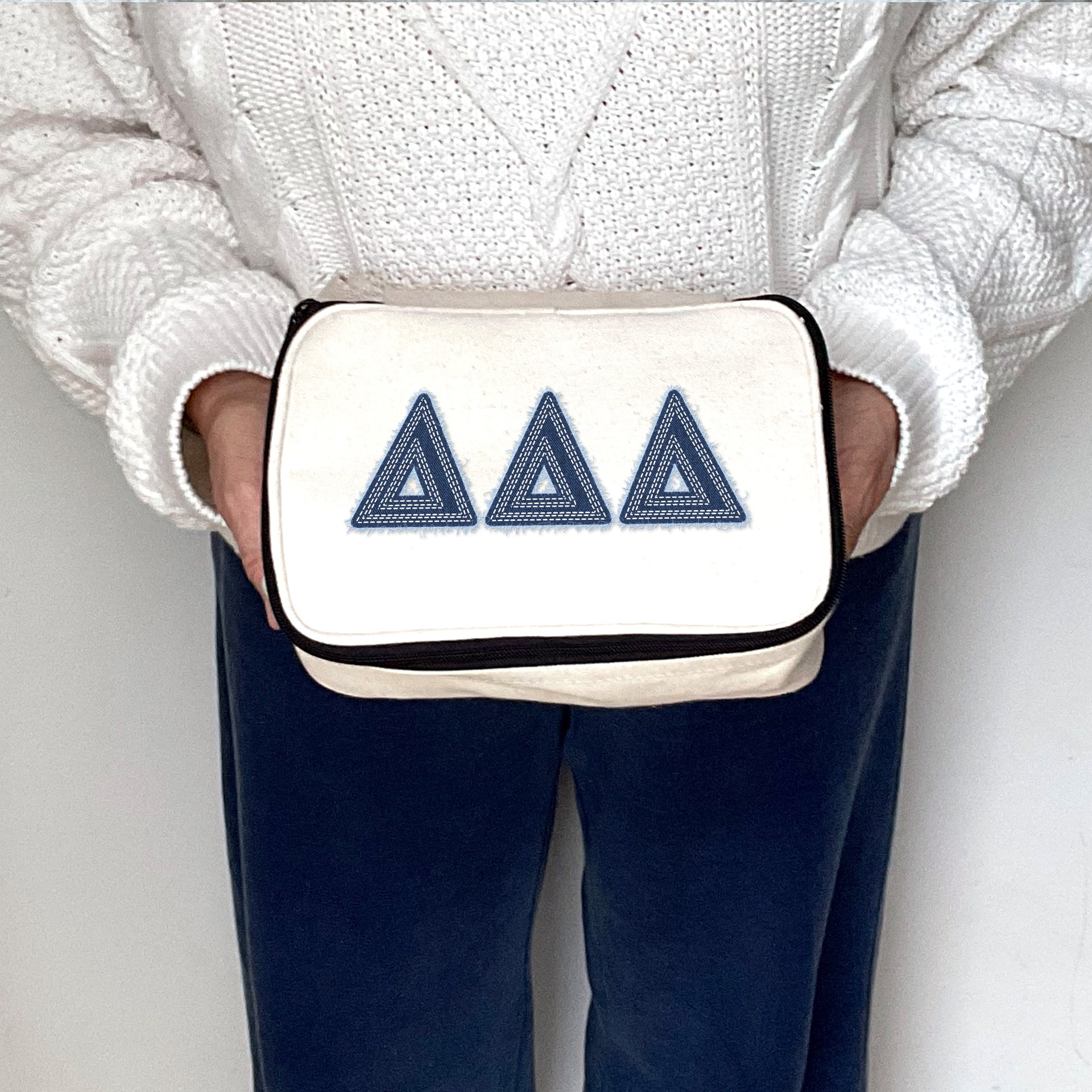 Delta Delta Delta canvas makeup bag featuring Tri Delta Greek letters in denim style, held by a sister.