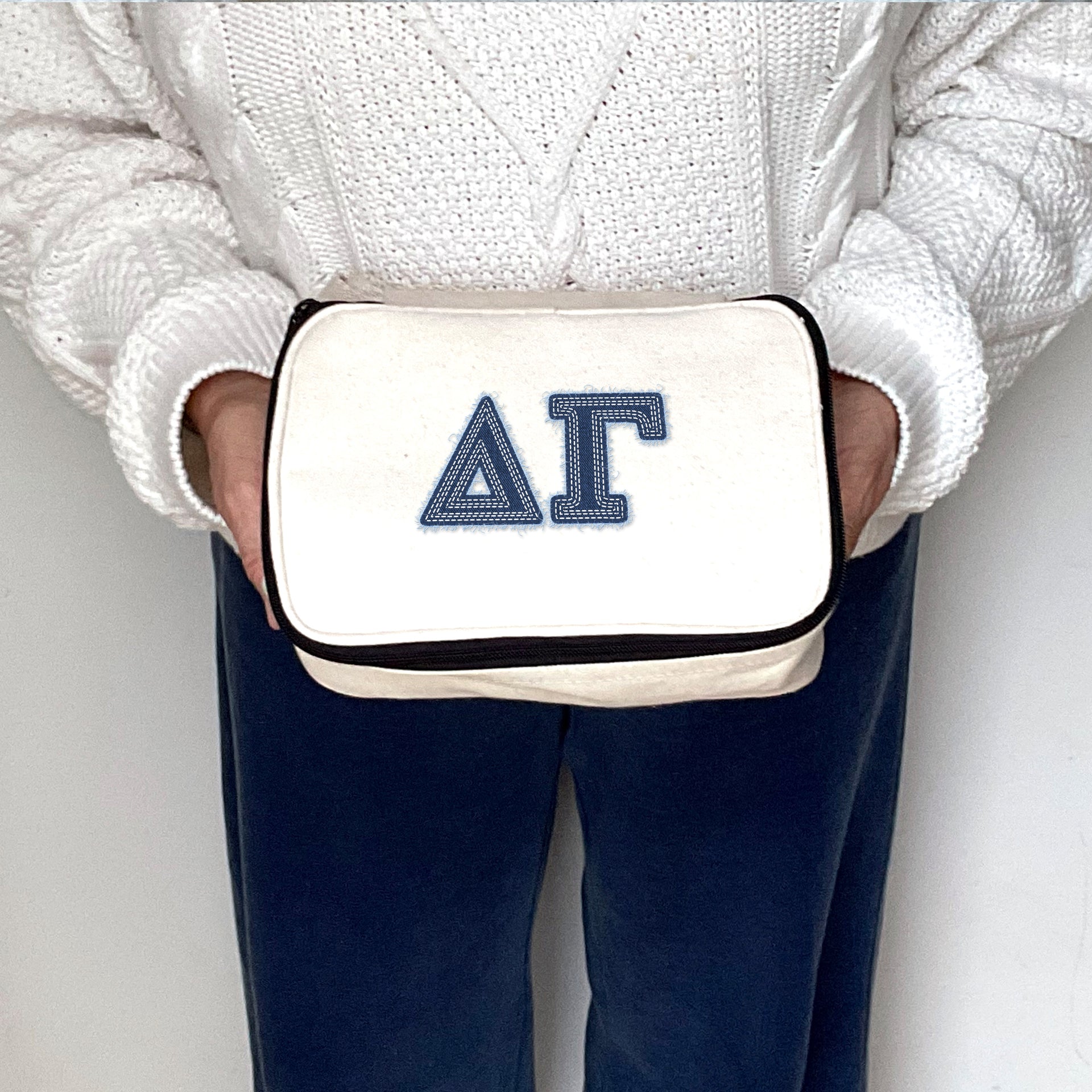 Delta Gamma canvas pouch featuring DG letters in denim-style font, held as a styled product image.