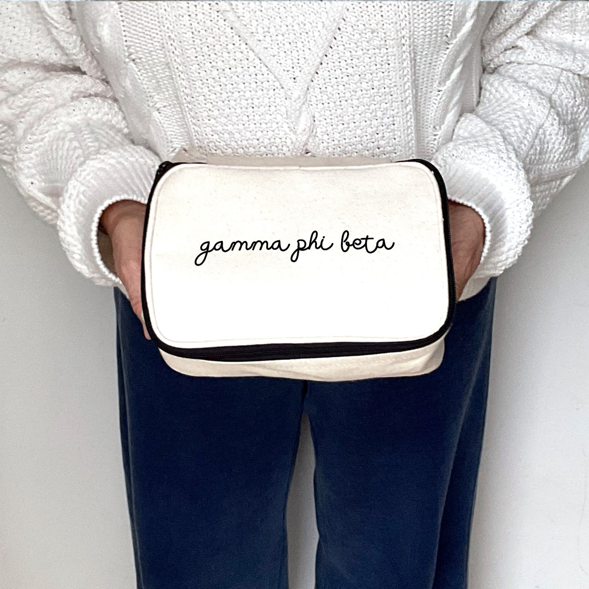 Gamma Phi Beta toiletry bag with script name design held by a woman, shown from mid-frame.
