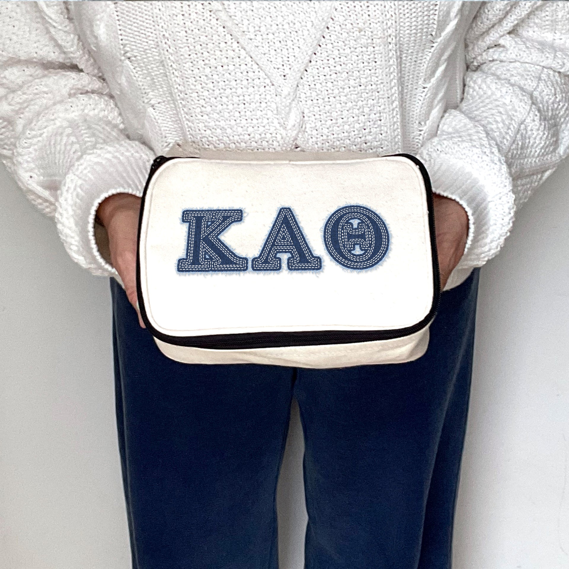 Kappa Alpha Theta denim-style Greek letter cosmetic bag for Theta, held by a sorority sister.
