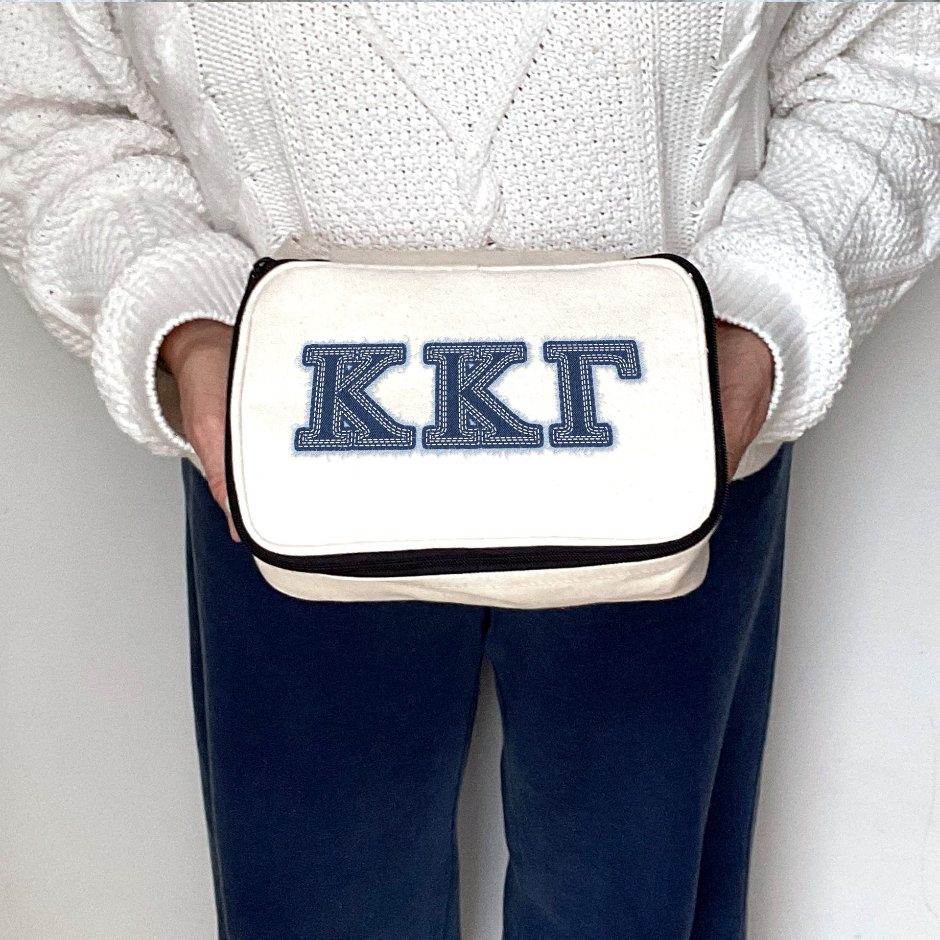 Kappa Kappa Gamma bag printed with KKG Greek letters in denim-style font, held in a styled shot.