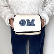 Phi Mu makeup pouch shown being held with denim-style Phi Mu letters printed on canvas.