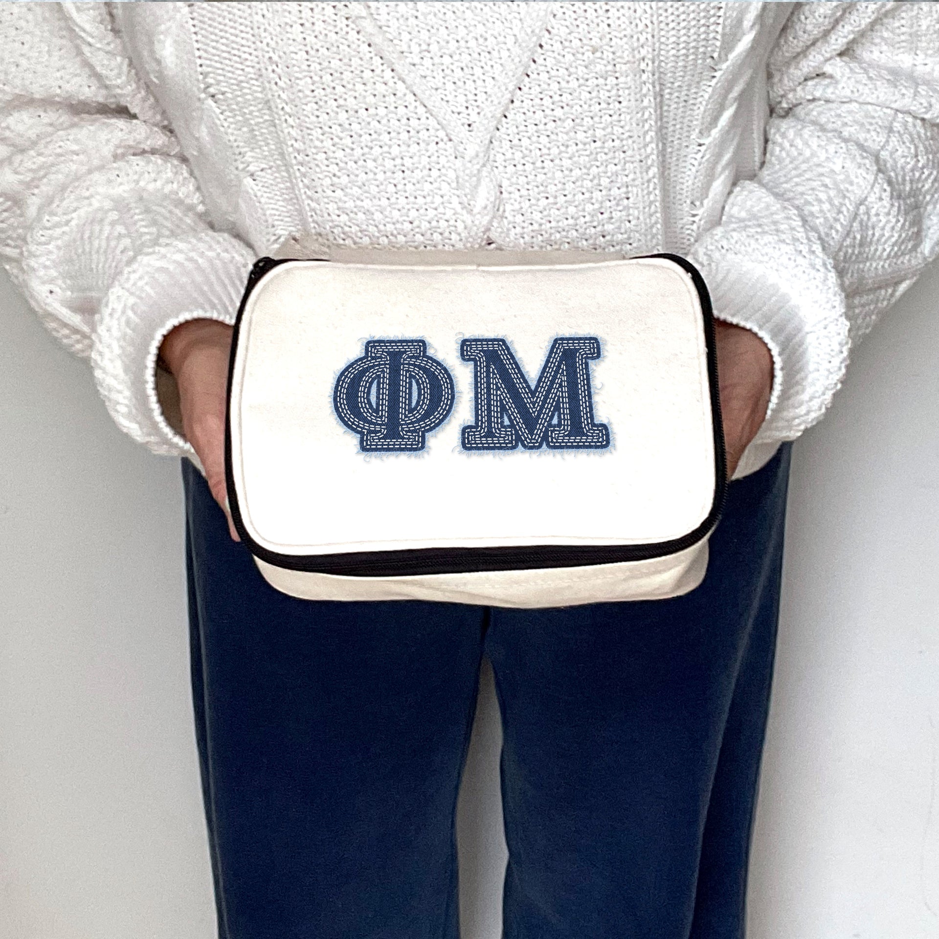 Phi Mu Phi Mu cosmetic pouch with denim-style Greek letters held for display by a sorority woman.