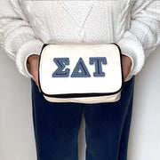 Sigma Delta Tau sorority member holding an SDT cosmetic bag with denim-look Greek lettering.