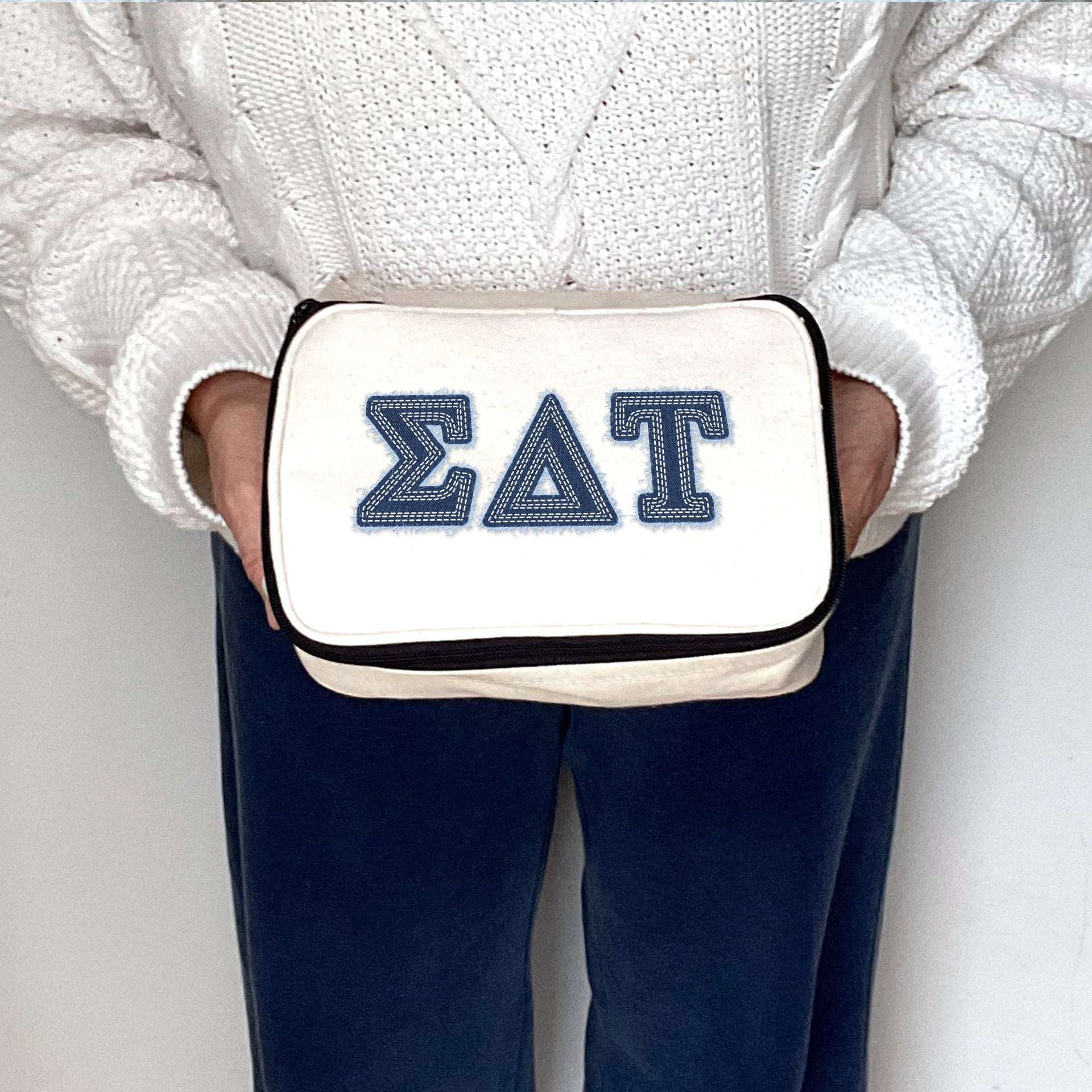 Sigma Delta Tau sorority member holding an SDT cosmetic bag with denim-look Greek lettering.