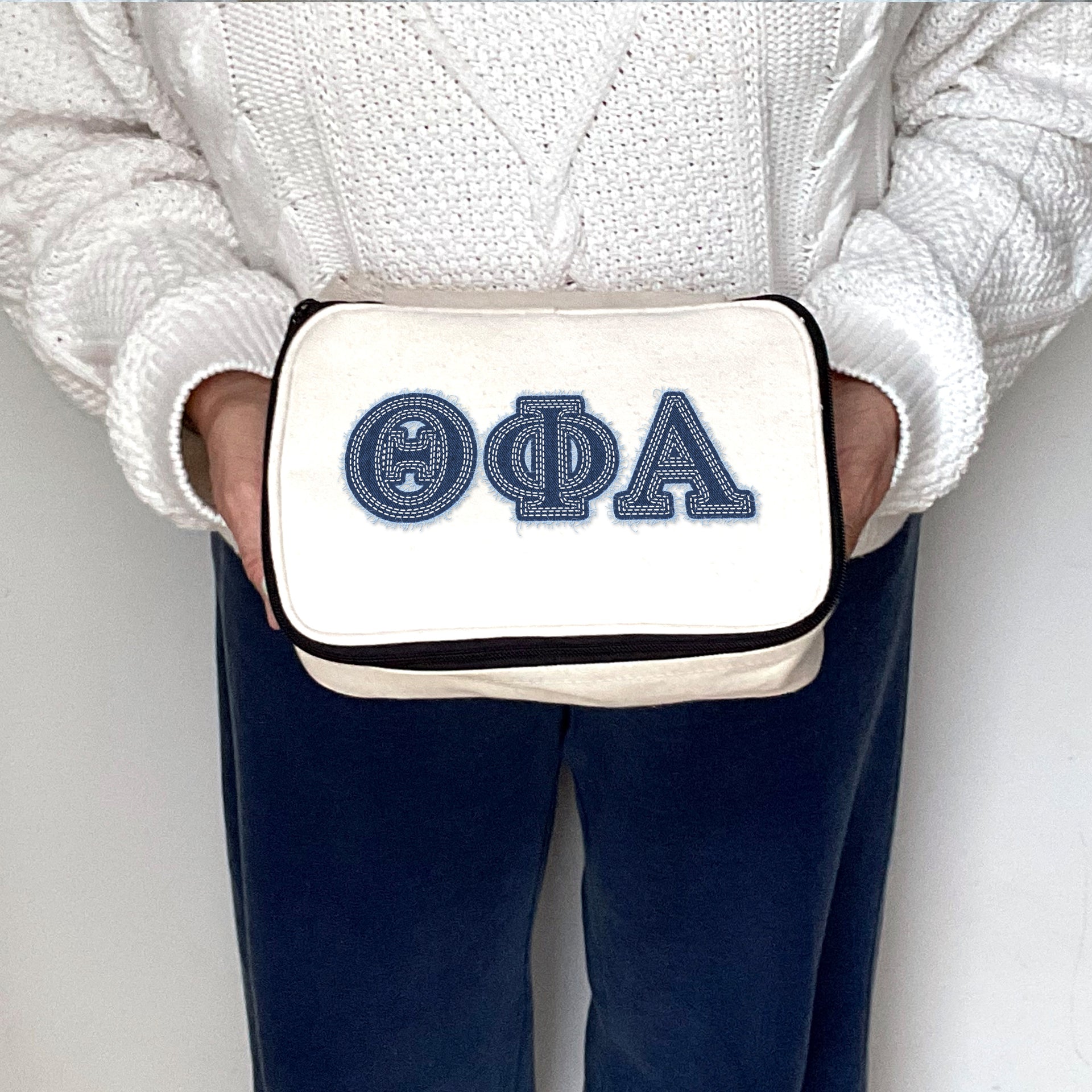Theta Phi Alpha Theta Phi Alpha sorority cosmetic bag with denim-style lettering, held for display.