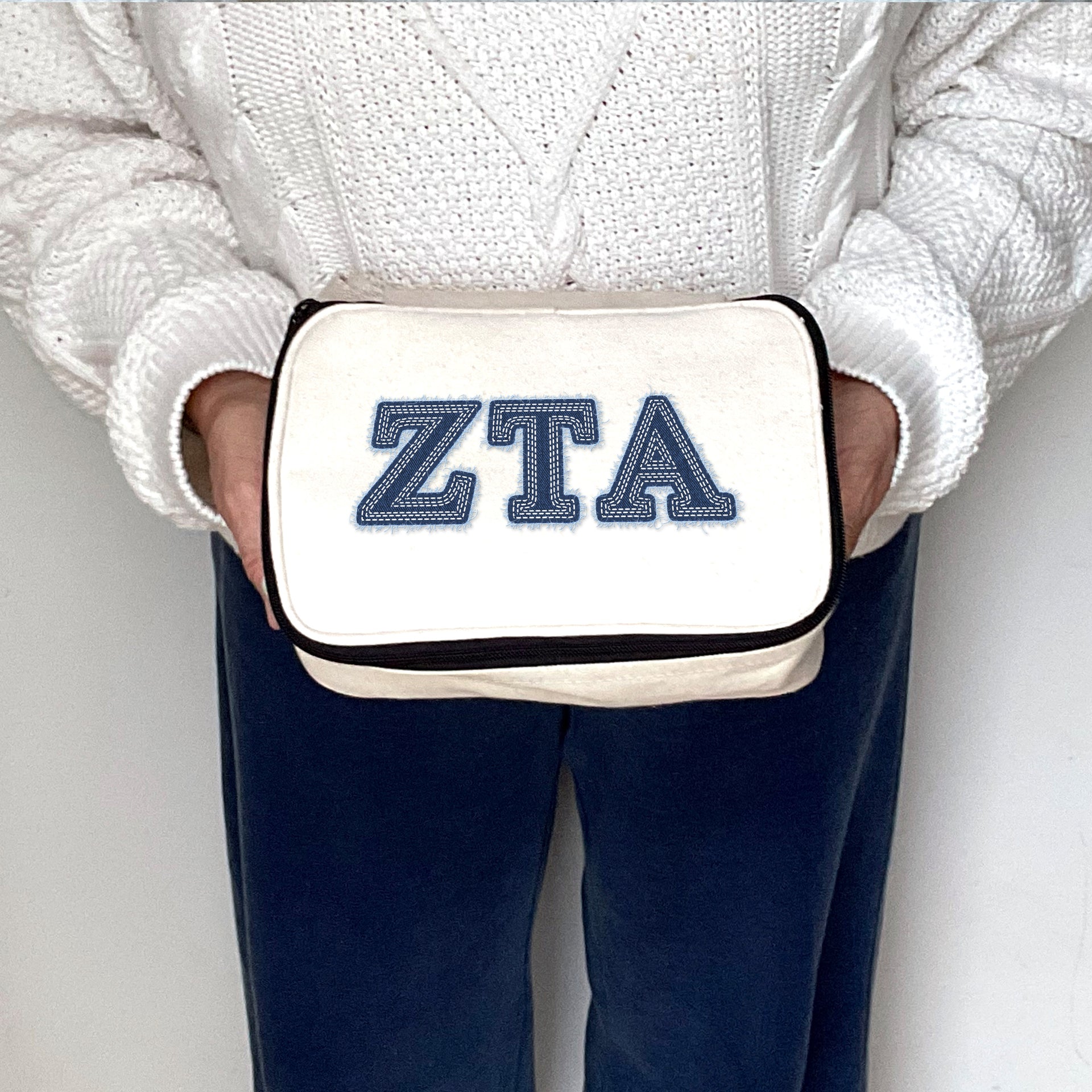 Zeta Tau Alpha pouch with ZTA letters printed in a denim-style design, held in product display.