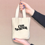 Chi Omega woman holding a cute Chi O tote bag, perfect for small essentials and Greek events.