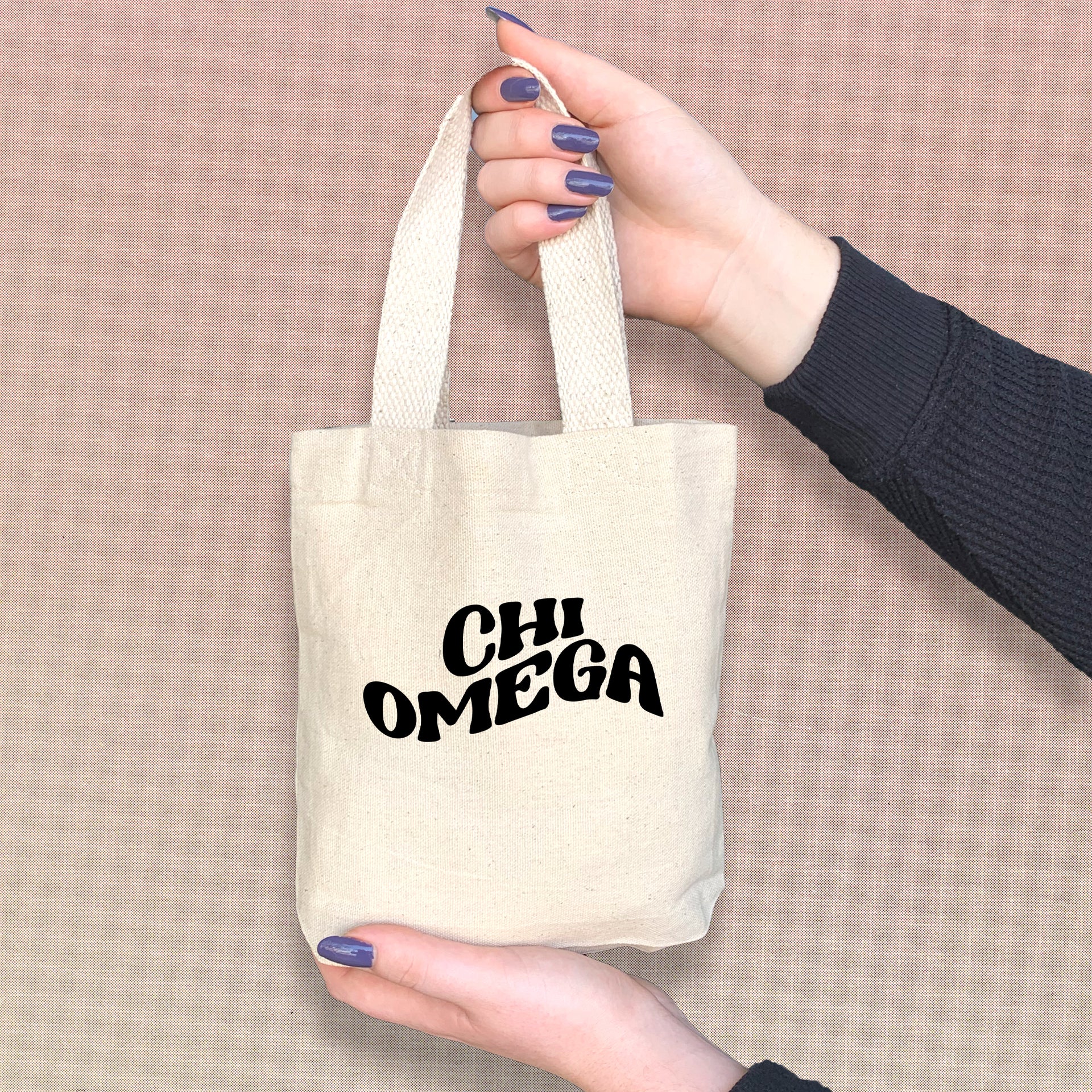 Chi Omega woman holding a cute Chi O tote bag, perfect for small essentials and Greek events.