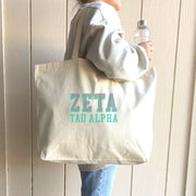 Zeta Tau Alpha tote bag with dimensional sorority letters, carried over the shoulder of a woman in ZTA gear.