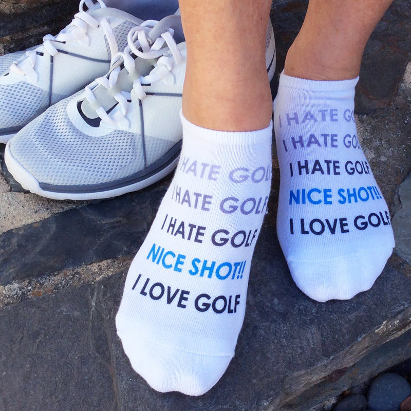 A pair of white no-show golf socks with the funny phrase "I HATE GOLF (NICE SHOT!!) I LOVE GOLF" printed on top, perfect for golfers who know the ups and downs of the game.