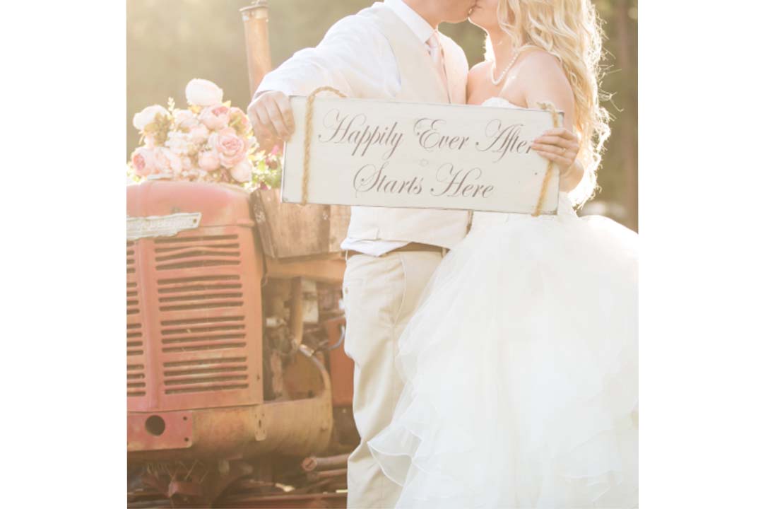 rustic country wedding couple in front of red tractor with flowers