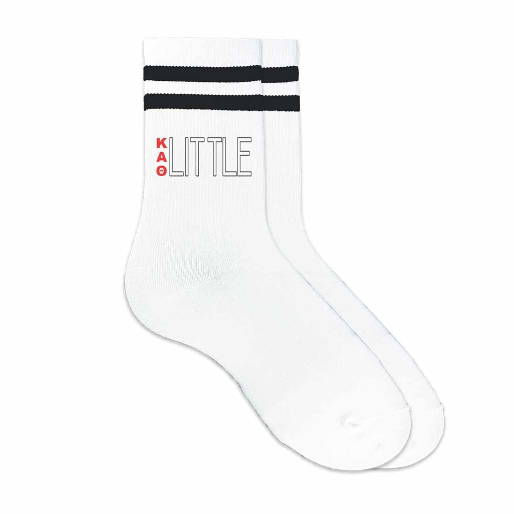 KAT Greek letters big or little design printed on the outside of the black striped crew socks.