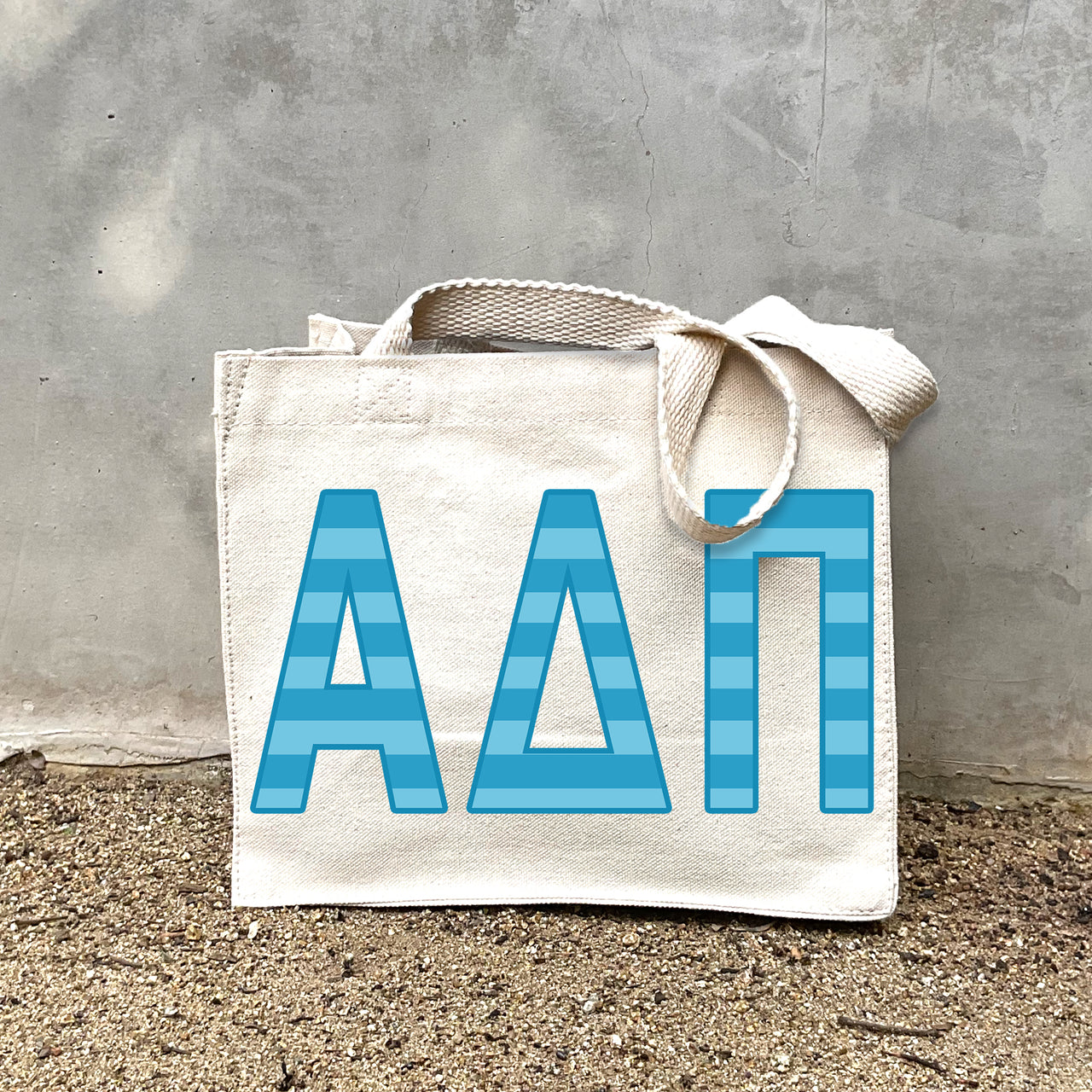 Model carrying the Alpha Delta Pi Greek letters in sorority colors small striped tote.