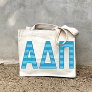 Model carrying the Alpha Delta Pi Greek letters in sorority colors small striped tote.