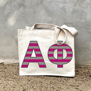 Model carrying the Alpha Phi Greek letters in sorority colors small striped tote.